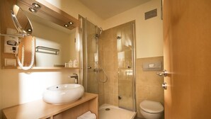Un baño moderno con ducha de vidrio, lavamanos blanco y retrete.