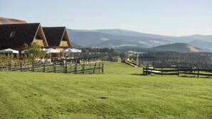 A rural setting with a barn, open-air seating, and a view of rolling hills. - Mein Hotel Fast (Wenigzell)