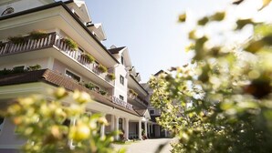 A multi-story hotel with balconies, a covered entrance, and a clear sky. - Mein Hotel Fast (Wenigzell)