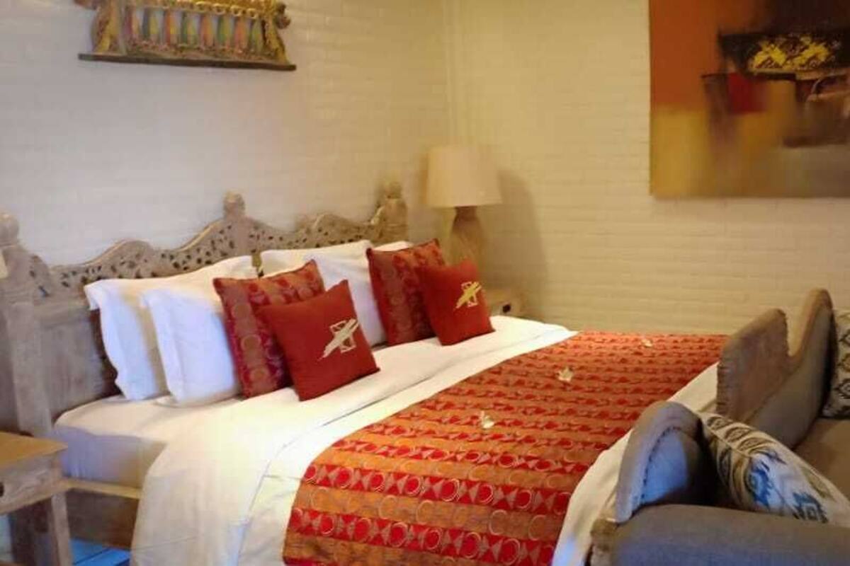 Een slaapkamer met een bed, een bank en een schilderij aan de muur.