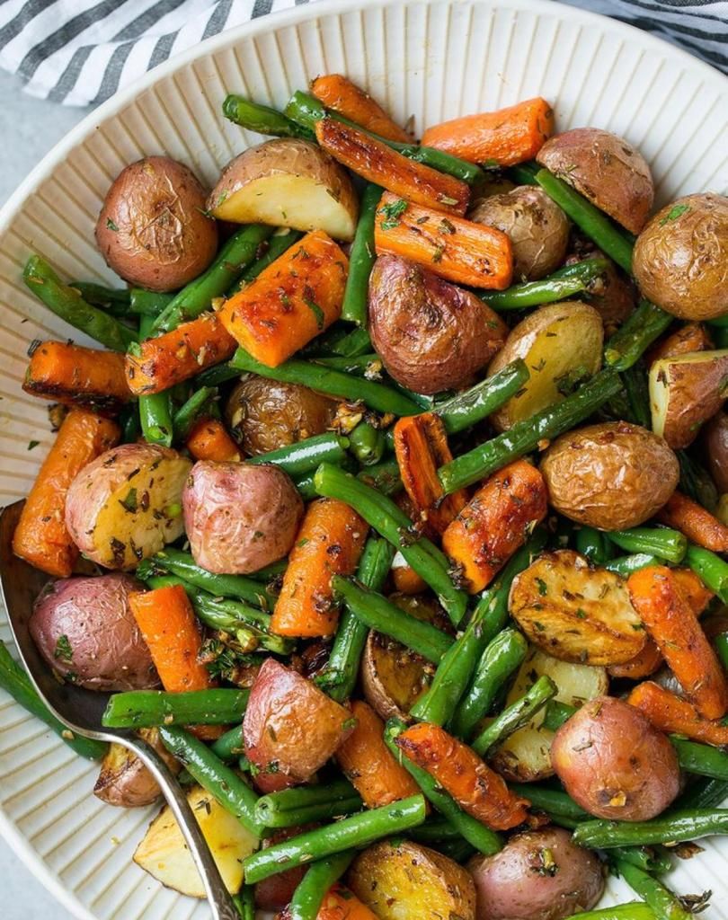 A bowl of roasted vegetables including potatoes, carrots, and green beans.