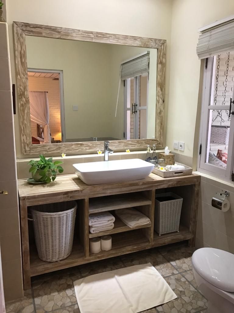 A bathroom with a wooden vanity, a large mirror, a white sink, and a toilet.