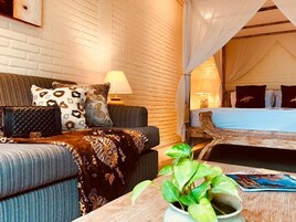 Una habitación con una cama, un sofá, una lámpara y una planta.