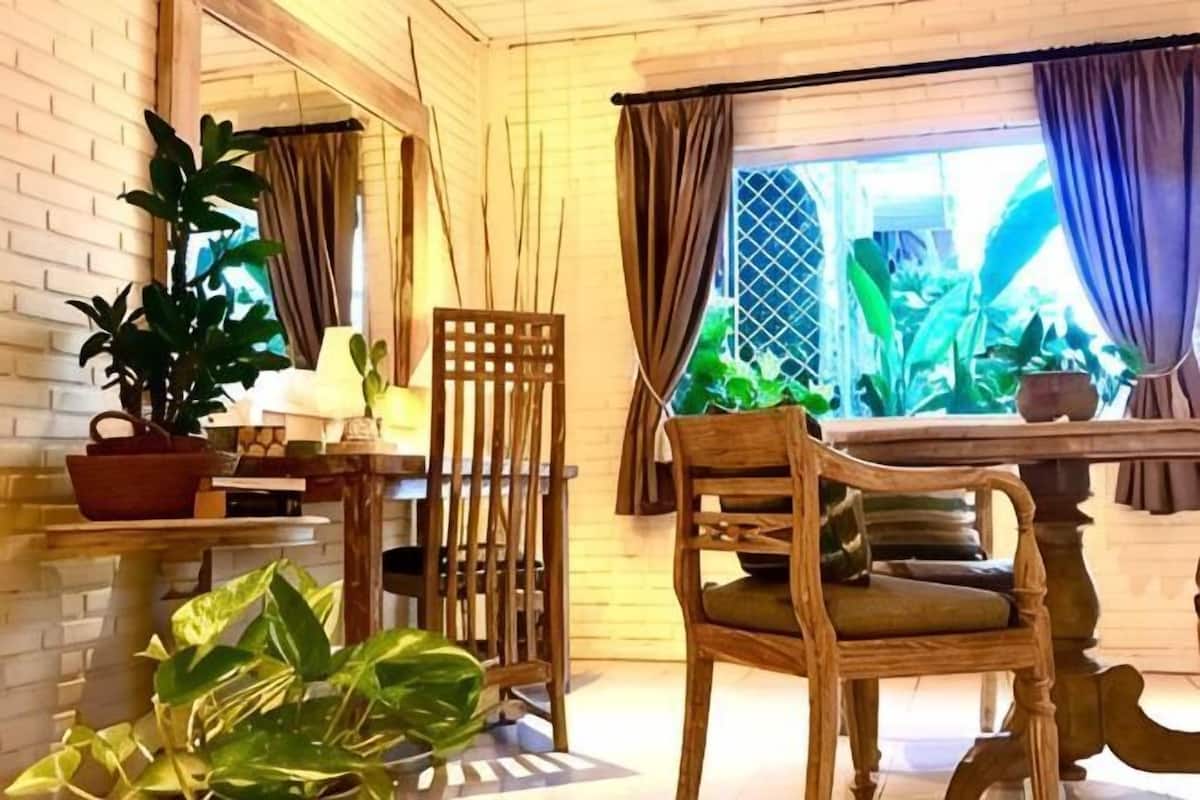 Een houten interieur met een eettafel, stoelen en potplanten.