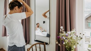 Una stanza con un grande specchio, un letto e una finestra con tende.