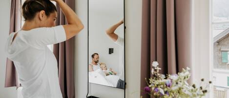 Una habitación con un espejo grande, una cama y un ventanal con cortinas.