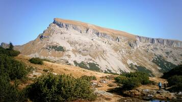 A mountainous landscape with a prominent rocky peak, a small stream, and sparse vegetation.