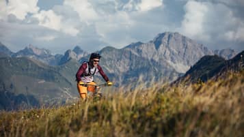 Un ciclista de montaña en un sendero con montañas al fondo.