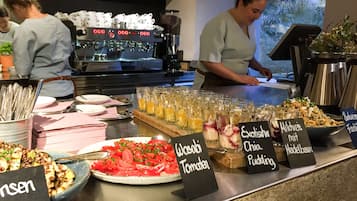 Un'area buffet con diverse opzioni di cibo e una macchina per il caffè sullo sfondo.