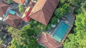 An aerial view of a residential area with multiple houses, a swimming pool, and lush greenery.