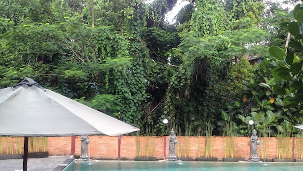 A swimming pool with statues, surrounded by a brick wall and lush greenery.