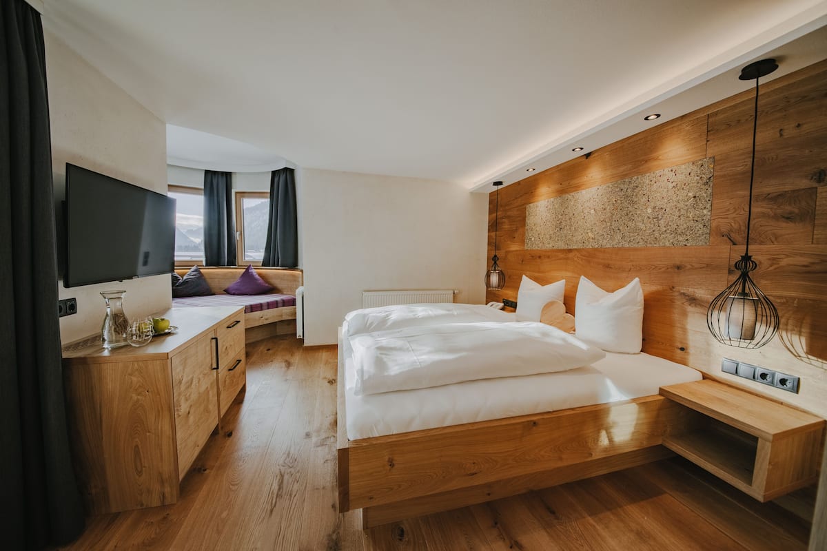Ein modernes Schlafzimmer mit einem Holzbett, einem Flachbildfernseher, einem Holztisch und einem Fenster mit Bergblick.