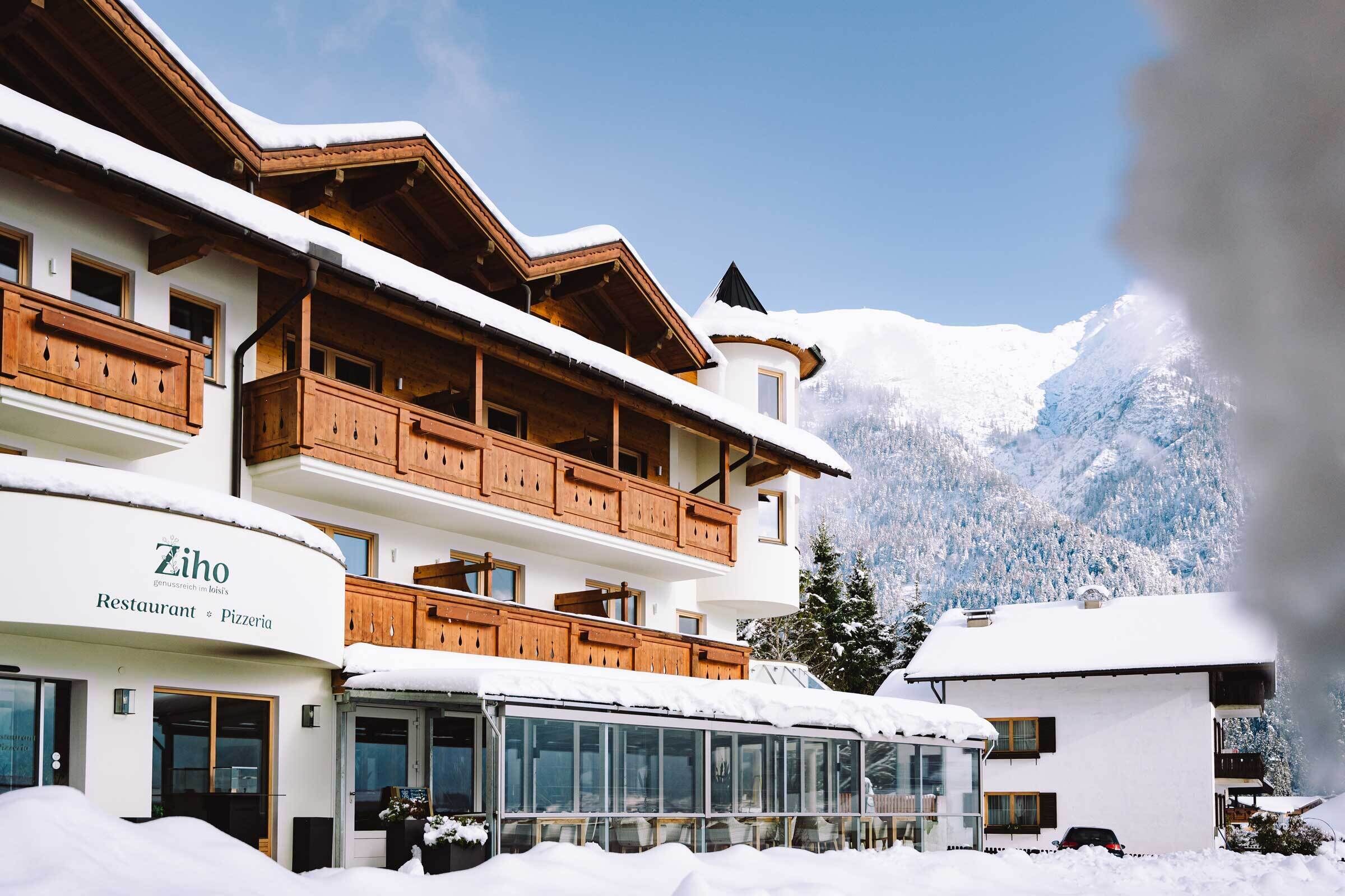 A multi-story building with wooden balconies and a restaurant named "Zihof Restaurant & Pizzeria" on the ground floor.