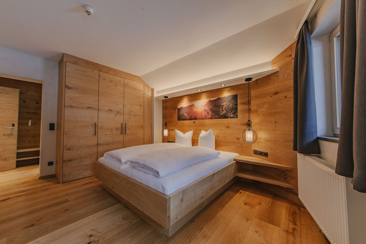 Ein modernes Schlafzimmer mit einem hölzernen Bett, Einbauschrank und einem großen Fenster.