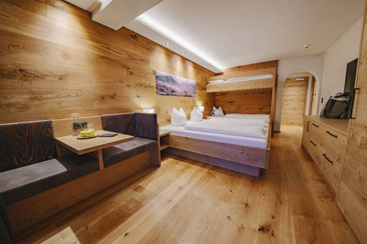 Ein holzgestaltetes Schlafzimmer mit einem Stockbett, einem kleinen Tisch mit einem Glas und einer Bank.