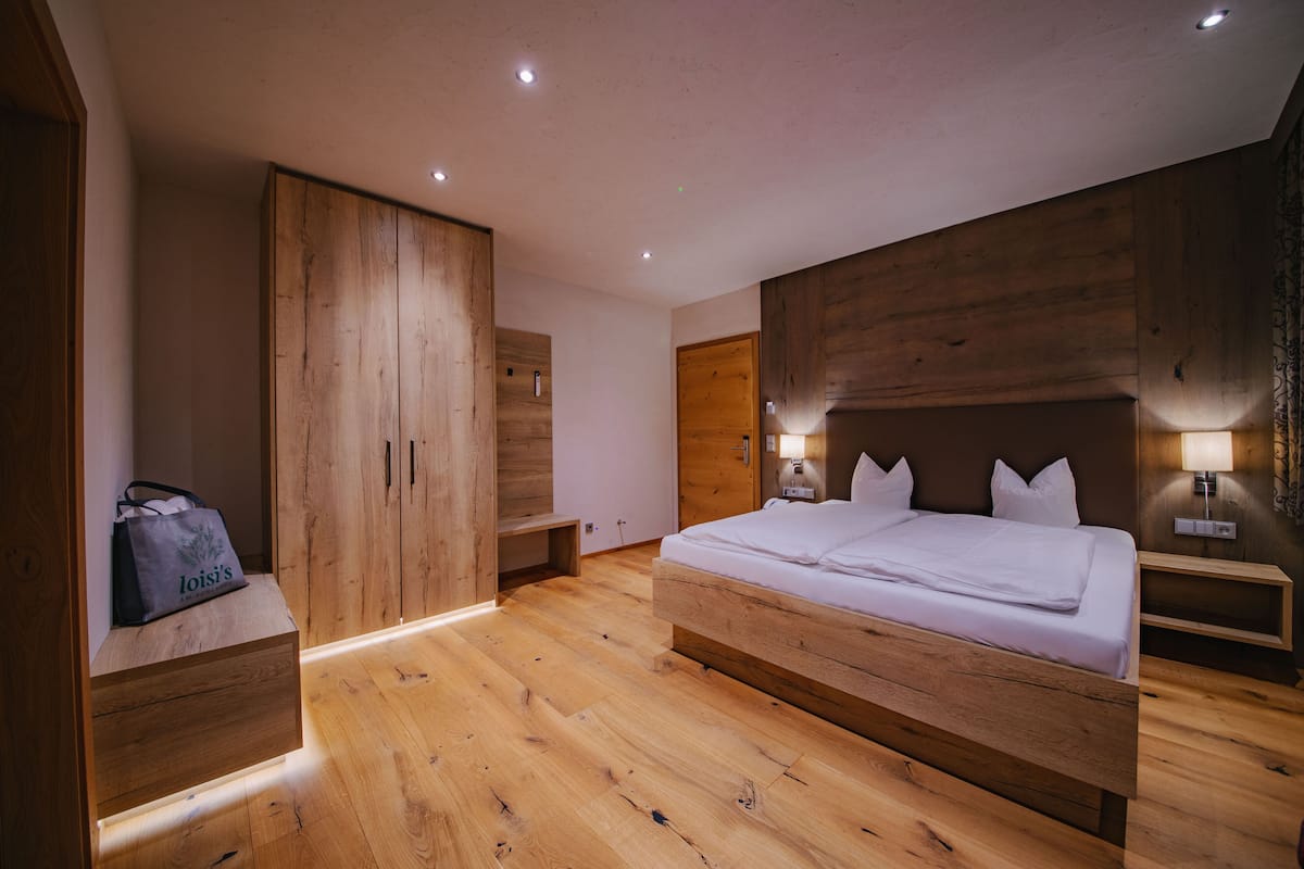 Ein Schlafzimmer mit einem hölzernen Bett, Nachttischen, einem Kleiderschrank und einer Bank.