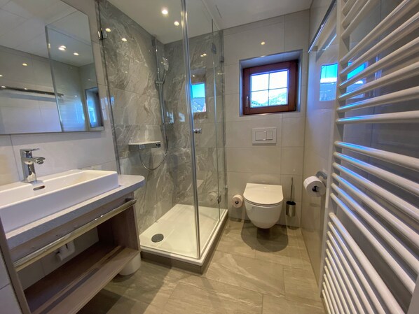 Un baño moderno con ducha envuelta en vidrio, inodoro y lavamanos.