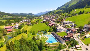Un complexe hôtelier doté d’une piscine, d’un petit lac et offrant une vue sur un paysage montagneux.