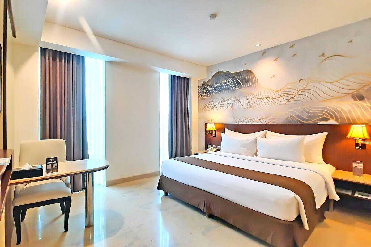 A hotel room with a bed, a desk, a chair, and a television.