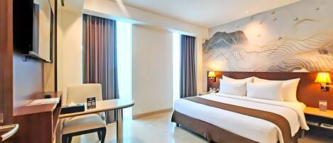 A hotel room with a bed, a desk, a chair, and a television.