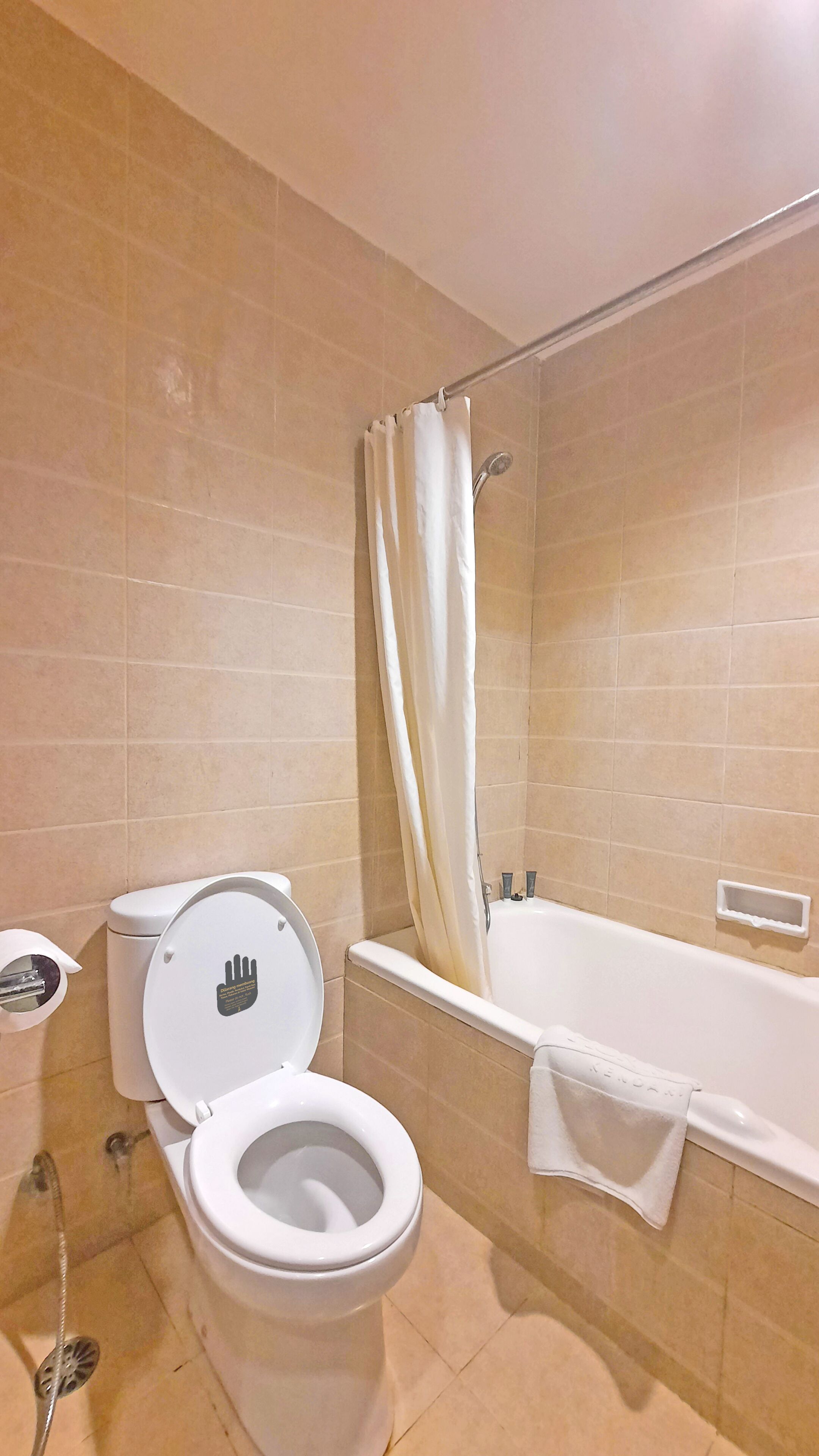 A bathroom with a toilet, a bathtub, and a shower curtain.