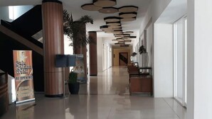 A hotel lobby with a polished floor, a reception desk, and a sign indicating the hotel is reopening. - Palu Golden (Palu)