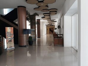 Een hotellobby met een gepoetste vloer, een receptiebalie en een bord waarop staat dat het hotel heropent.