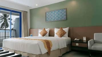 A hotel room with a bed, a chair, a nightstand, and a view of palm trees.