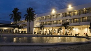 A hotel with a pool, palm trees, and multiple balconies. - Palu Golden (Palu)