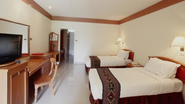 A hotel room with two beds, a desk with a television, and a chair. - Toraja Misiliana (Rinding Batu)