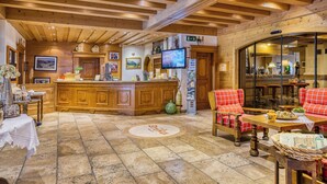 A cozy interior with a wooden bar area, seating, and a tiled floor. - Hotel Erika (Nauders)