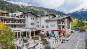 A hotel with a restaurant, outdoor seating, and a view of snow-capped mountains. - Hotel Erika (Nauders)