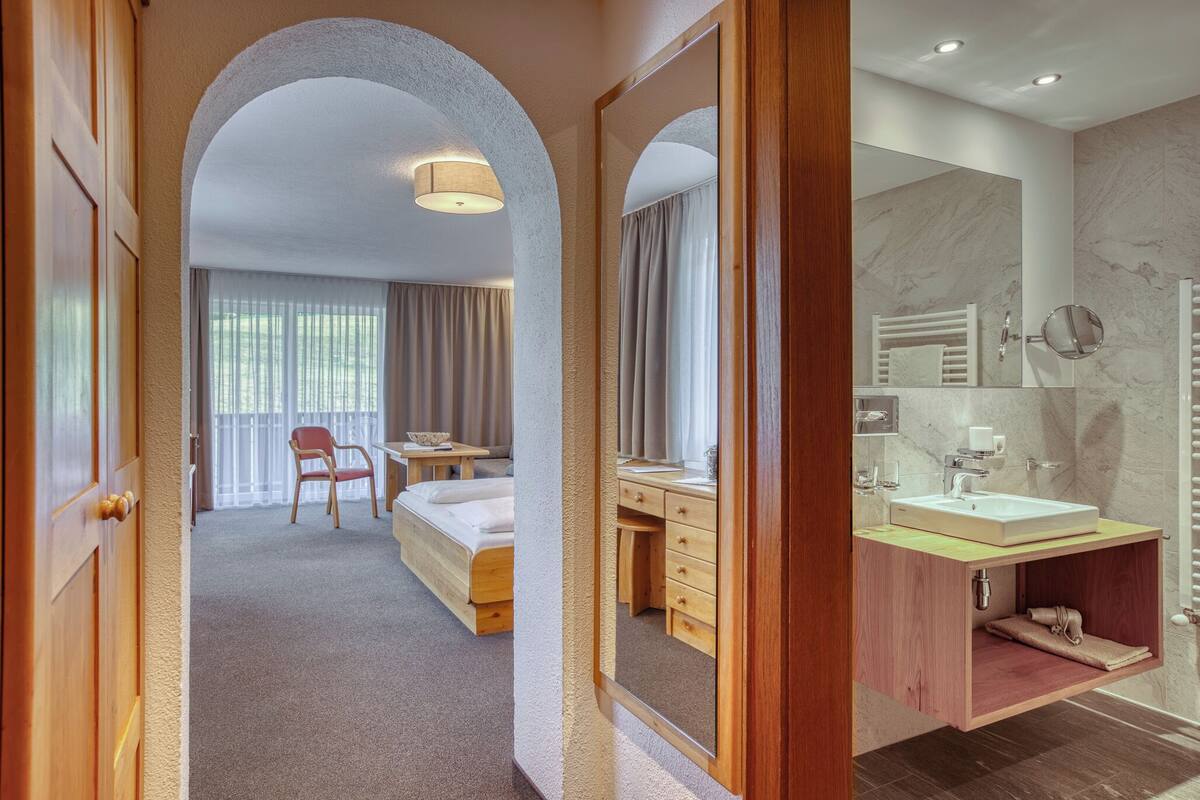 A hotel room with a bed, desk, and bathroom.