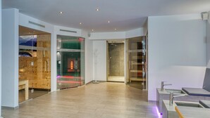 A modern spa area with wooden walls, a reception desk, and a seating area with a massage table. - Hotel Erika (Nauders)