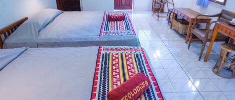 A room with two beds, a wooden table, chairs, and a bench.