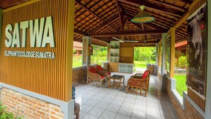 A covered outdoor seating area with wicker furniture and a sign reading "SATWA ELEPHANTECOLLEGE SUMATRA". - The Satwa Elephant Ecolodge (Labuhan Ratu)