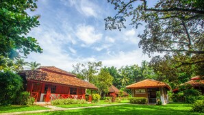 A traditional building with a tiled roof, surrounded by lush greenery and palm trees. - The Satwa Elephant Ecolodge (Labuhan Ratu)