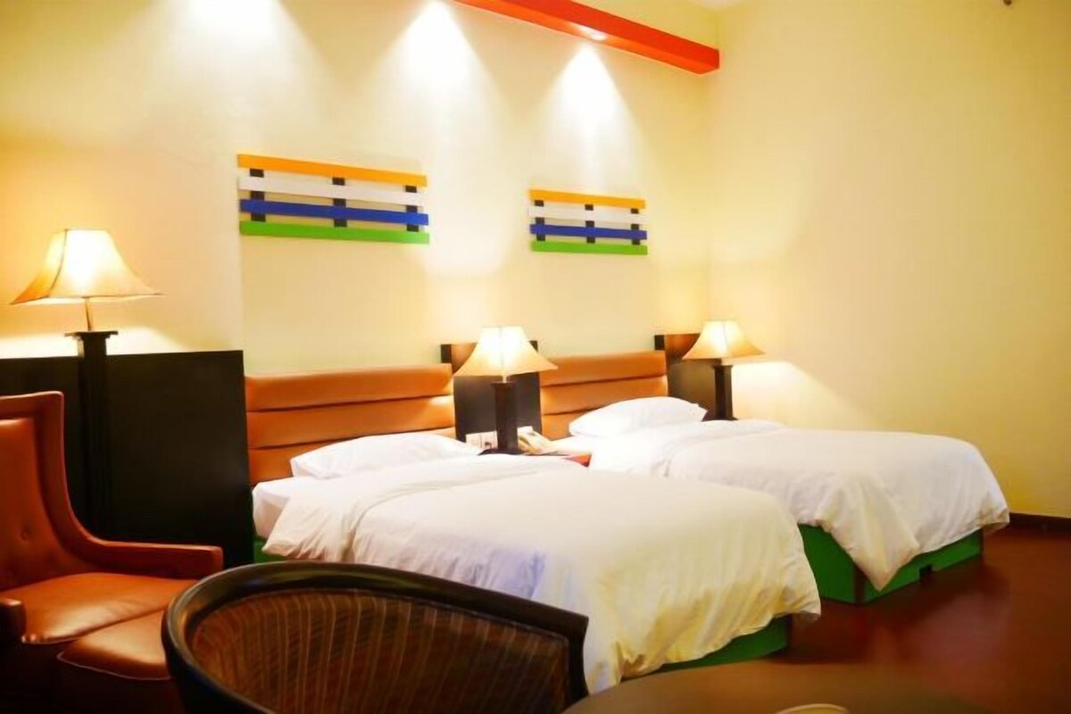 Ein Hotelzimmer mit zwei Betten, einem Sessel und zwei Wandlampen.