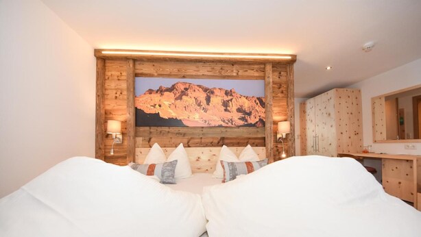 A bedroom with a mountain view, wooden headboard, and a bed with white linens. - Gasthof Martha (Nauders)