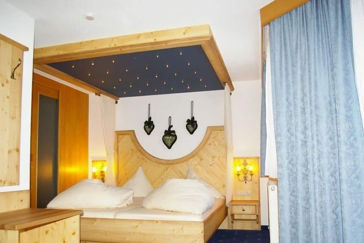 A wooden bed with a curved headboard, two bedside lamps, and a nightstand.