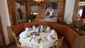 A dining area with a round table set for four, surrounded by wooden chairs with a leopard print cushion. - Gasthof Martha (Nauders)