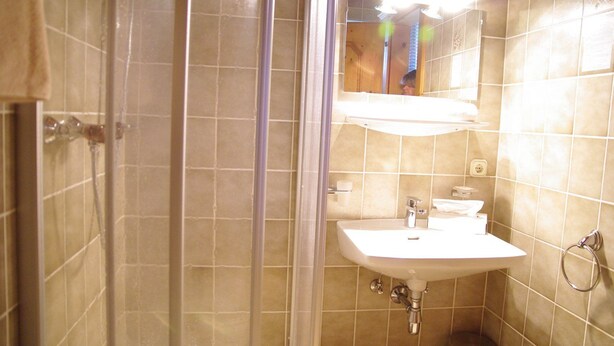 Un baño con ducha, lavabo y espejo.