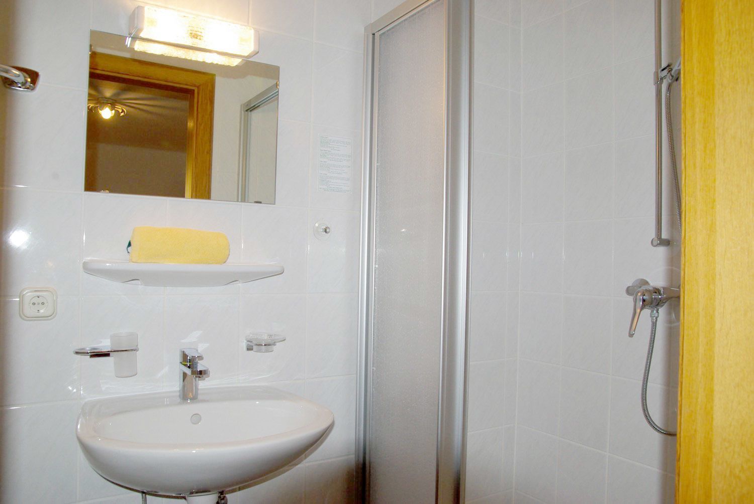 A bathroom with a sink, mirror, and shower.