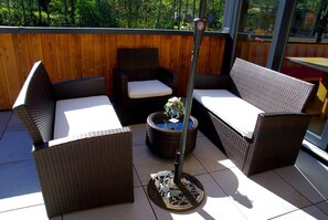 A patio with wicker furniture, including two chairs and a table with a flower vase. - Hotel Pension Heike (Aurach bei Kitzbuehel)