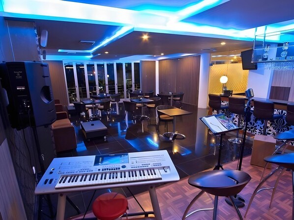 A music studio with a keyboard, stools, and a soundproofed room. - Splash Hotel Bengkulu (BENGKULU)