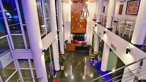 A modern hotel lobby with a central seating area, large windows, and a decorative chandelier. - Splash Hotel Bengkulu (BENGKULU)