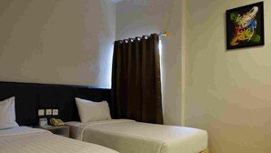 A hotel room with two beds, a nightstand with a phone, and a window with curtains. - Splash Hotel Bengkulu (BENGKULU)