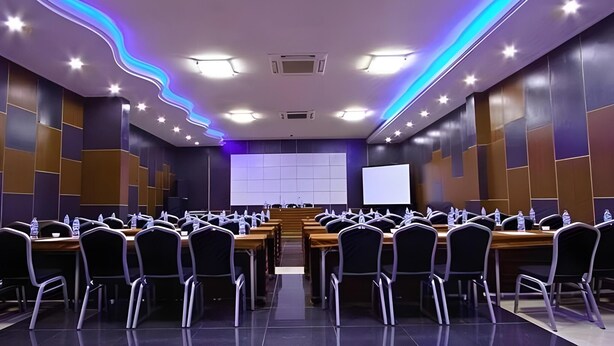 A conference room with a long table, chairs, a projector screen, and a whiteboard. - Splash Hotel Bengkulu (BENGKULU)
