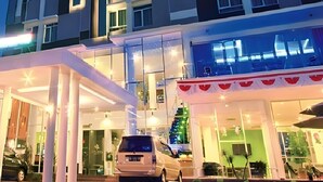 A modern hotel with a glass facade, a covered entrance, and a Christmas tree decoration. - Splash Hotel Bengkulu (BENGKULU)