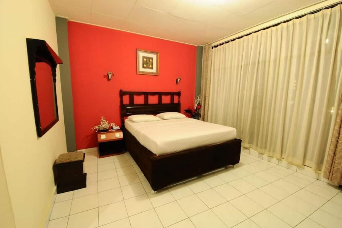 A bedroom with a bed, nightstand, and a mirror on the wall.